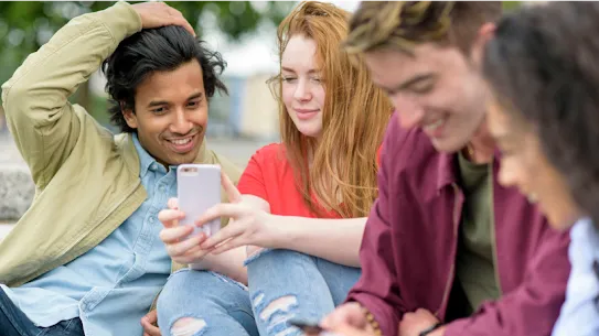 Un grupo de jóvenes sonrientes que comparten información en sus smartphones